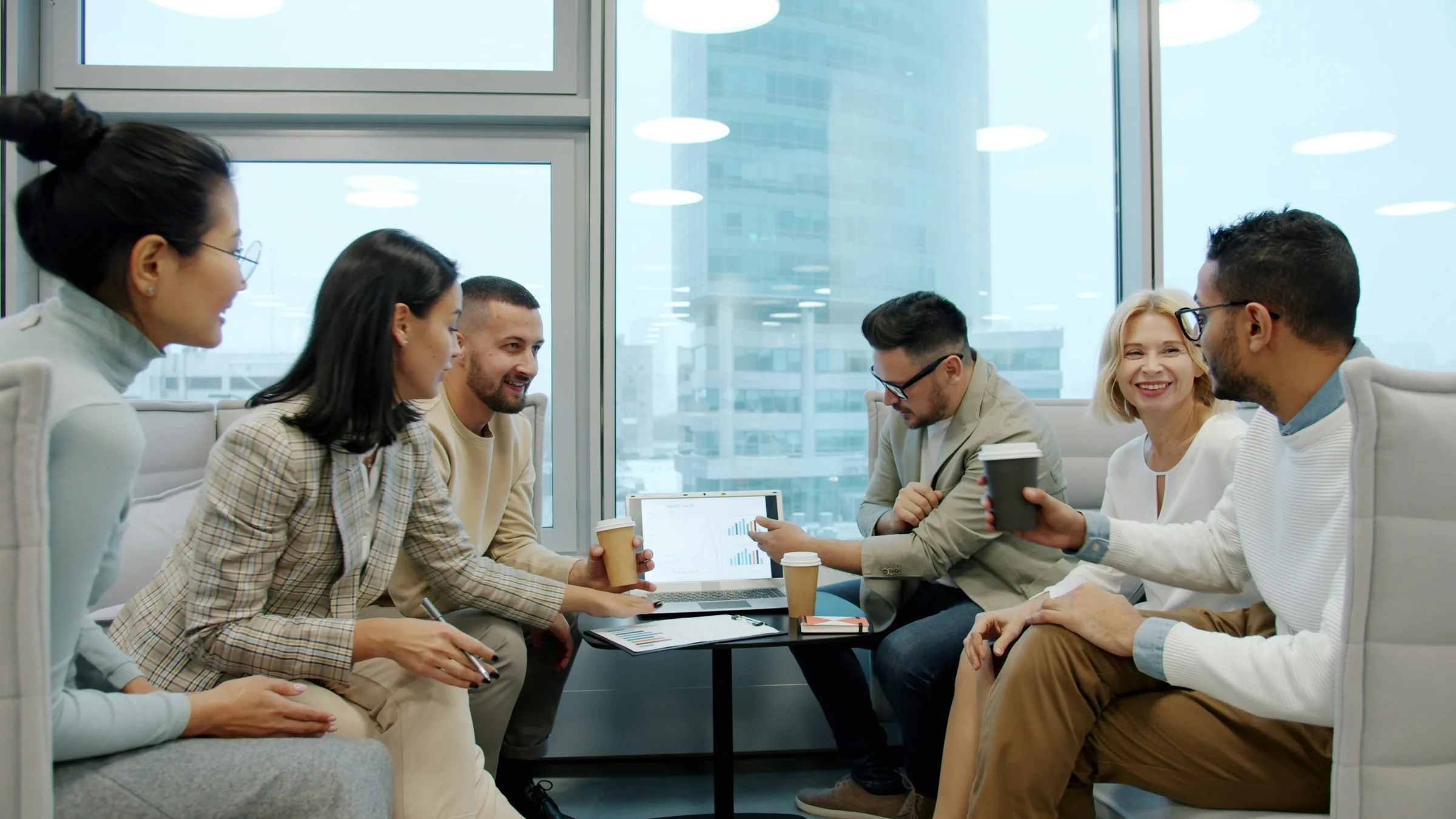 A project team collaborating around a laptop and shared work materials