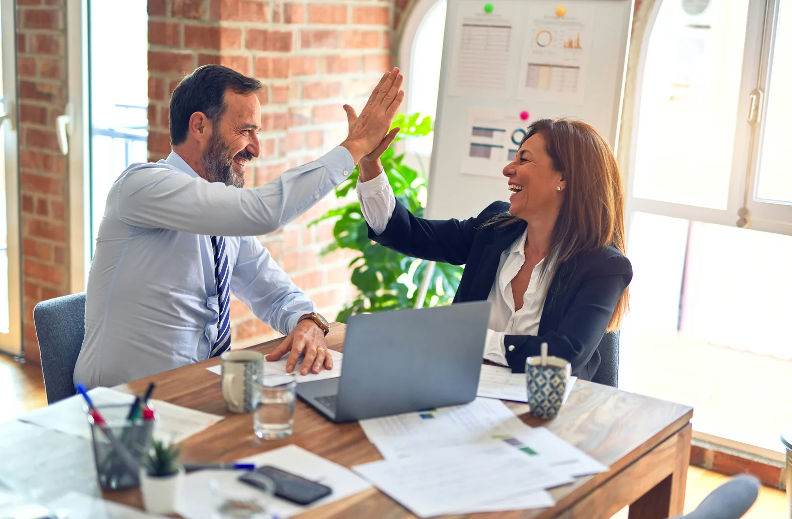 Two financial-services professionals celebrating successful collaboration in an office